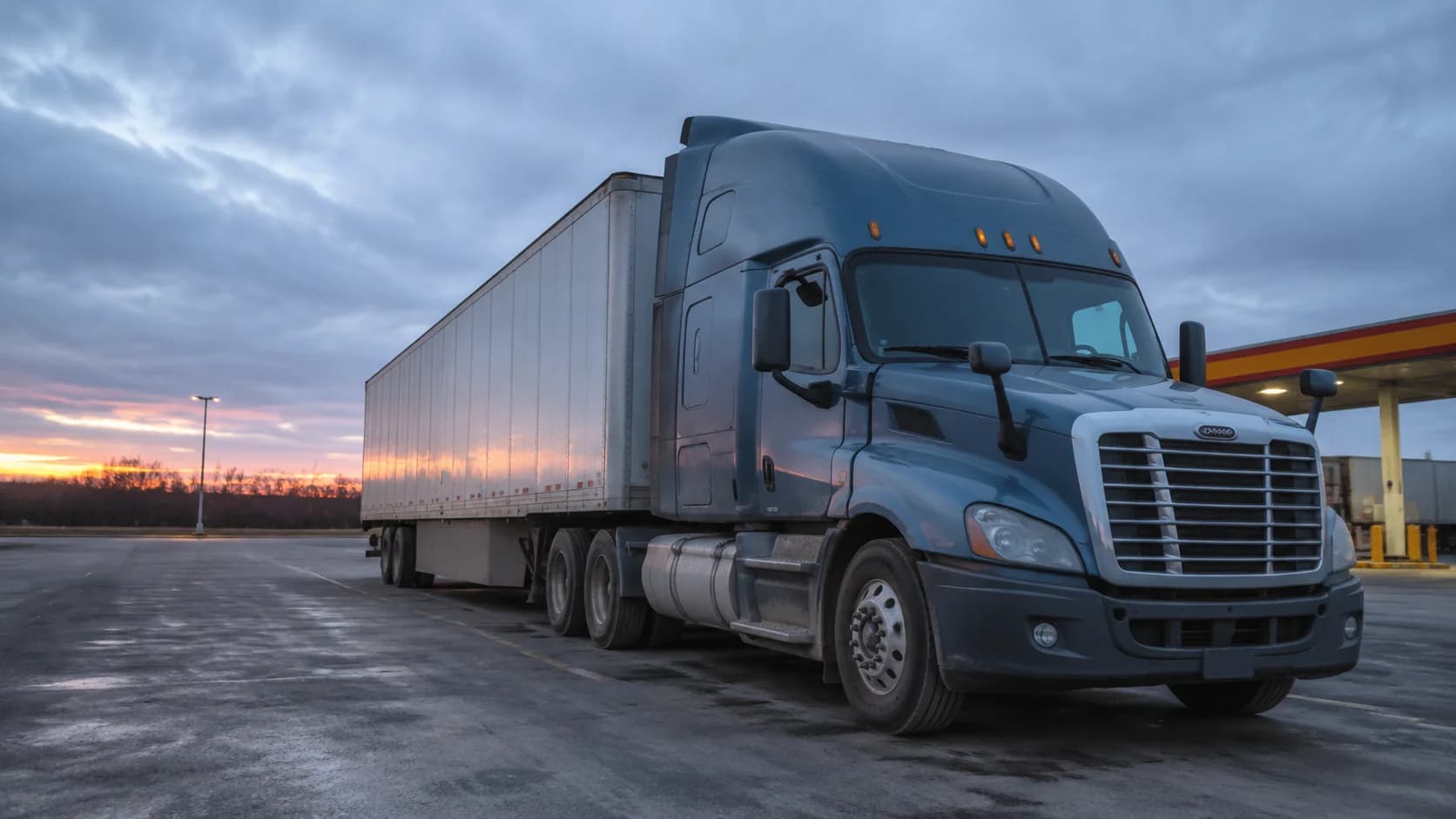 A semi truck parked at a rest area at dawn
