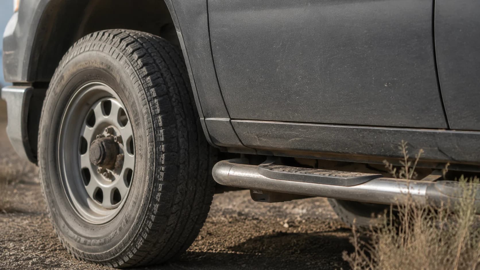 The wheel and lower door of a work truck parked on gravel